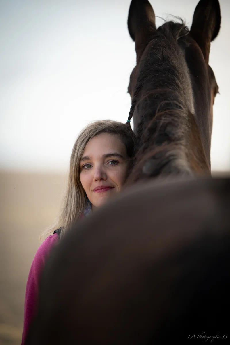 Portrait d'une jeune femme souriante, joue contre le museau d'un cheval