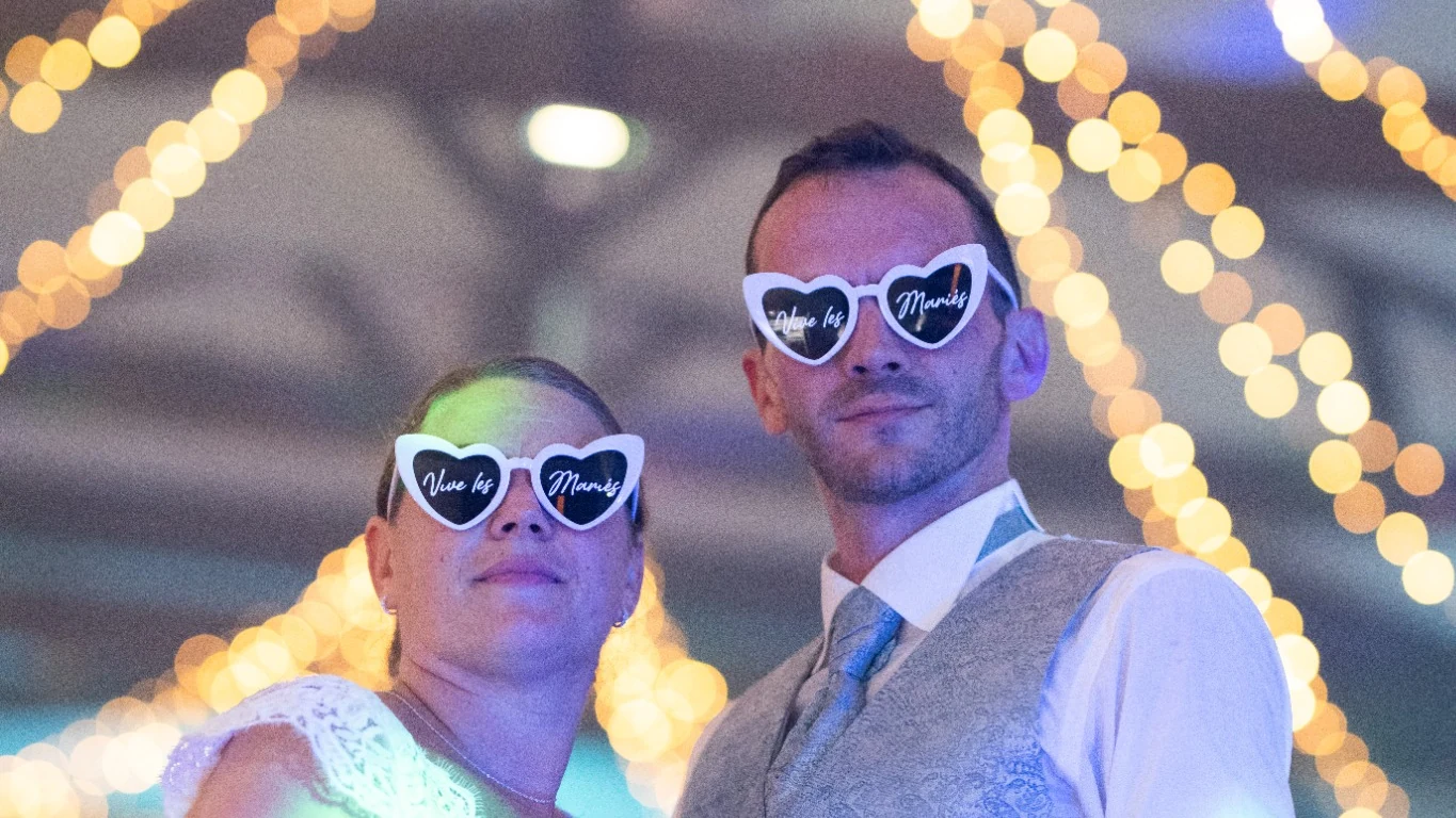 Les mariés portant des lunettes en forme de cœur, sous les guirlandes lumineuses après leur ouverture de bal