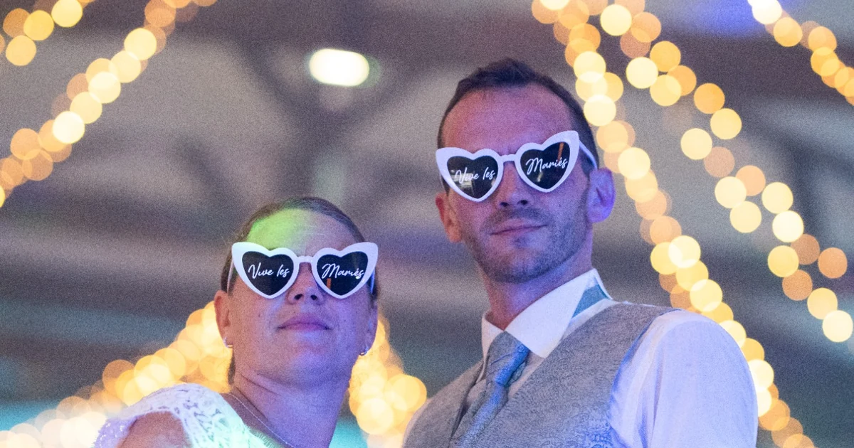 Les mariés portant des lunettes en forme de cœur, sous les guirlandes lumineuses après leur ouverture de bal
