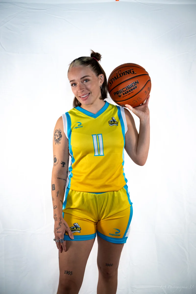 Portrait souriant d'une basketteuse en maillot jaune tenant son ballon