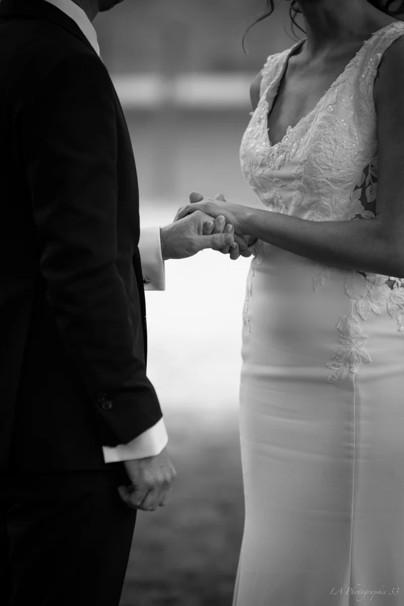 Photo en noir et blanc de mariés se tenant la main pendant leur cérémonie laïque
