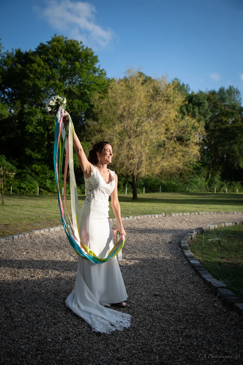 Mariée riante faisant virevolter des rubans colorés attachés à son bouquet