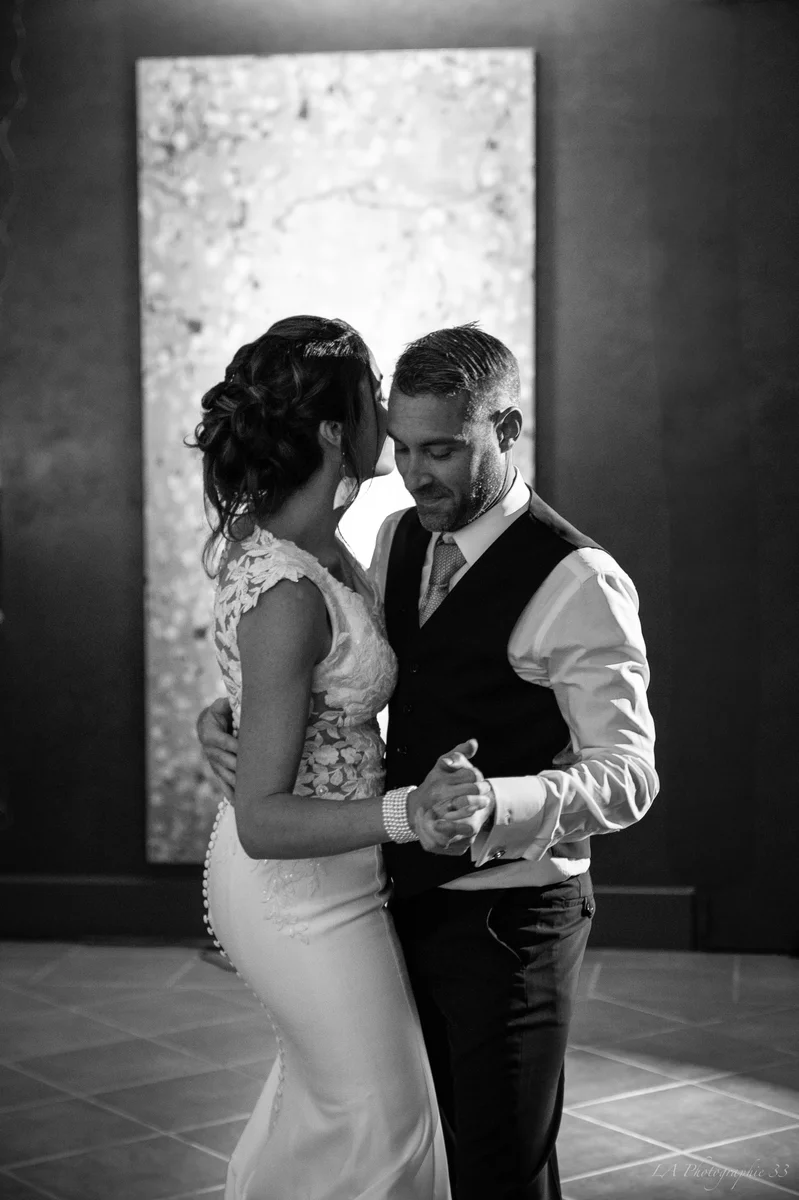 Photo en noir et blanc des mariés dansant leur première danse