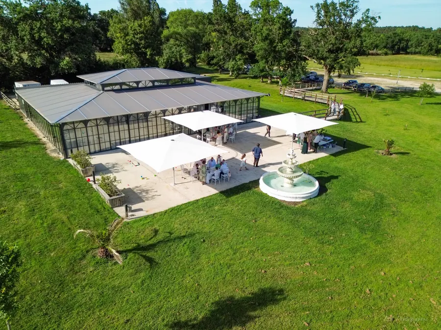 Vue aérienne au drone du domaine avec sa verrière et sa fontaine, invités profitant de la terrasse