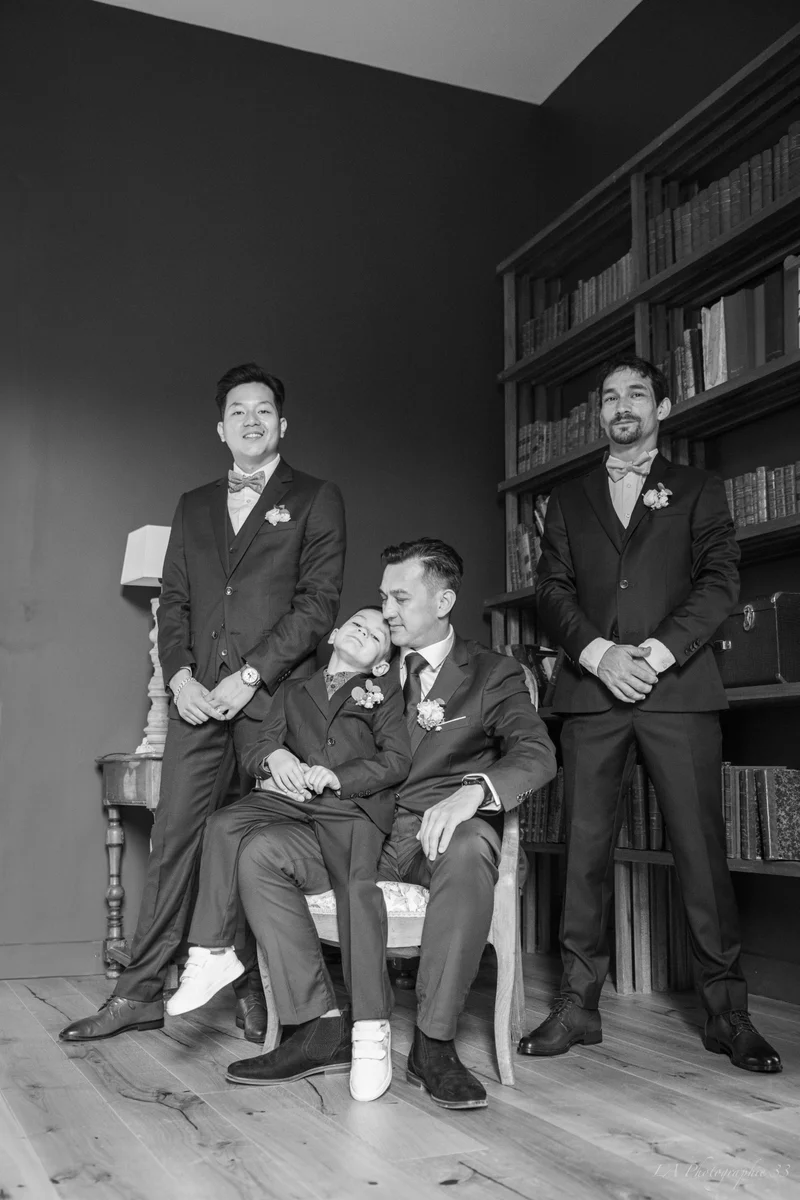 Photo en noir et blanc du marié et de ses témoins posant dans une bibliothèque