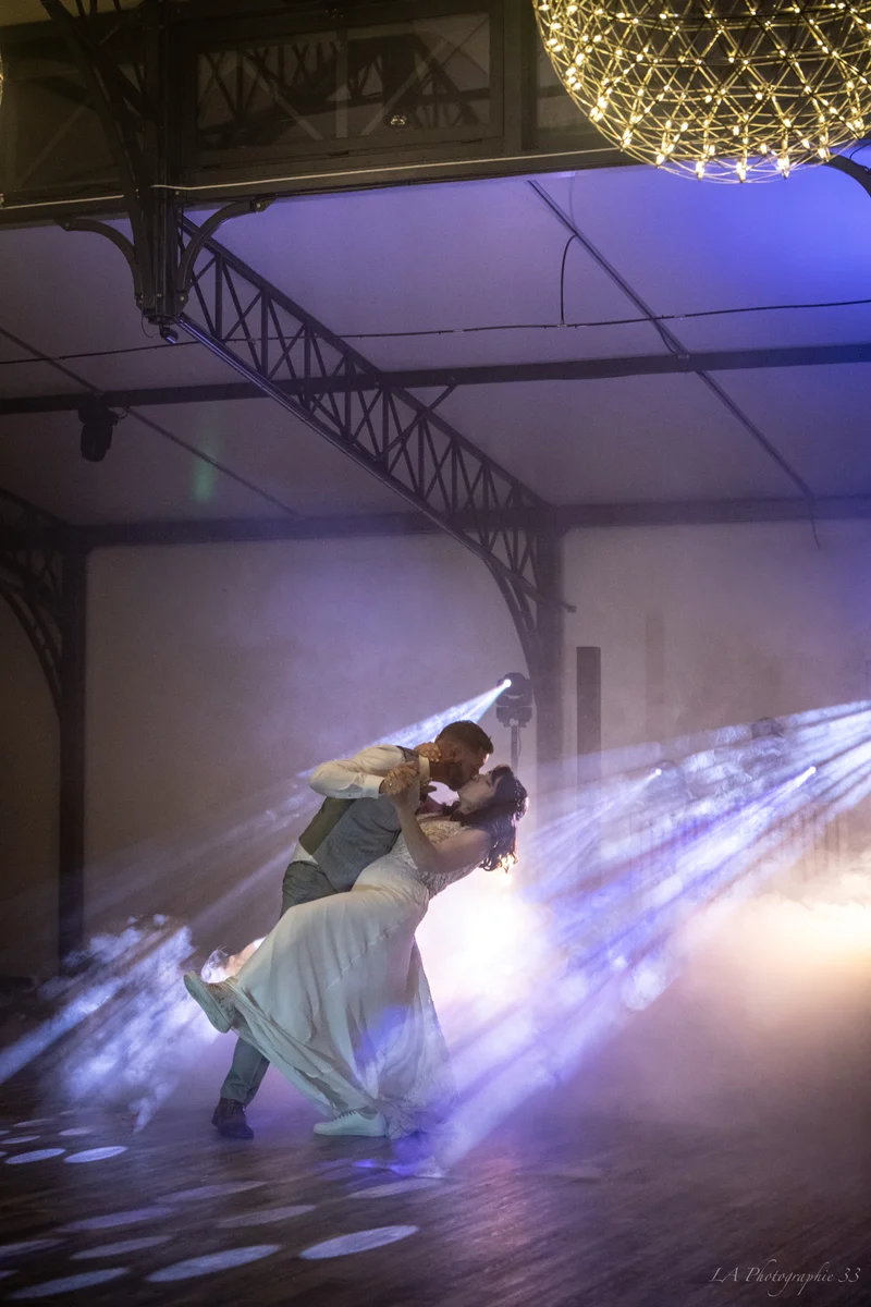 Mariés dansant un tango dramatique sous des faisceaux de lumière et de la fumée