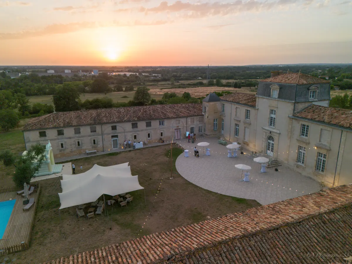 Vue aérienne au drone d'un domaine avec château, cour de réception et coucher de soleil