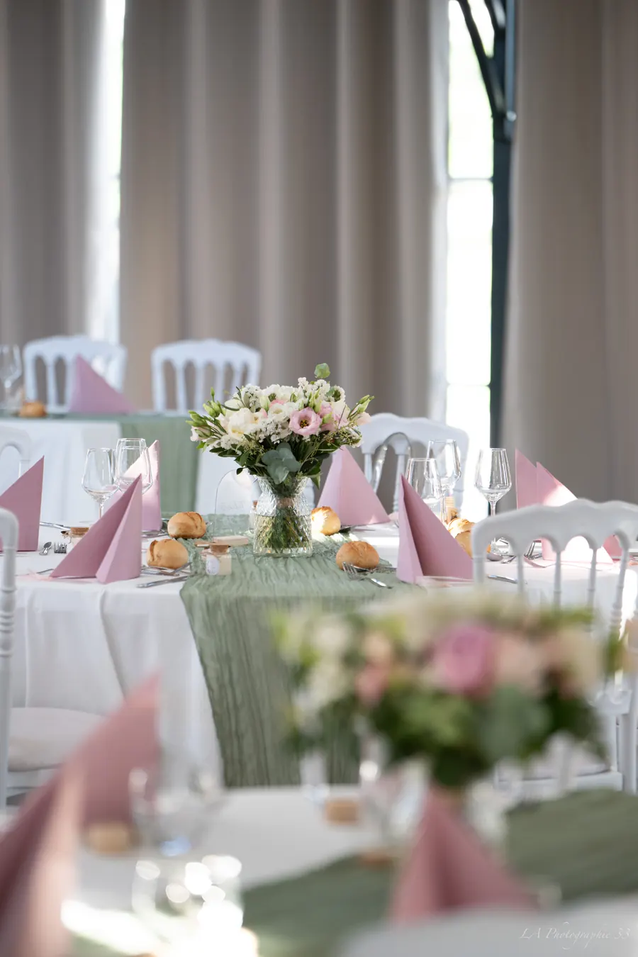 Table de réception dressée avec bouquet, serviettes roses et pain
