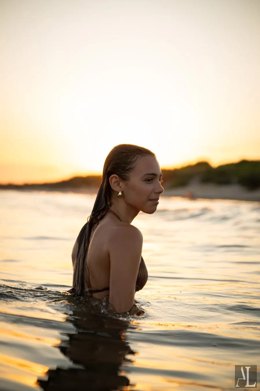 Jeune femme de profil dans l'eau au coucher de soleil