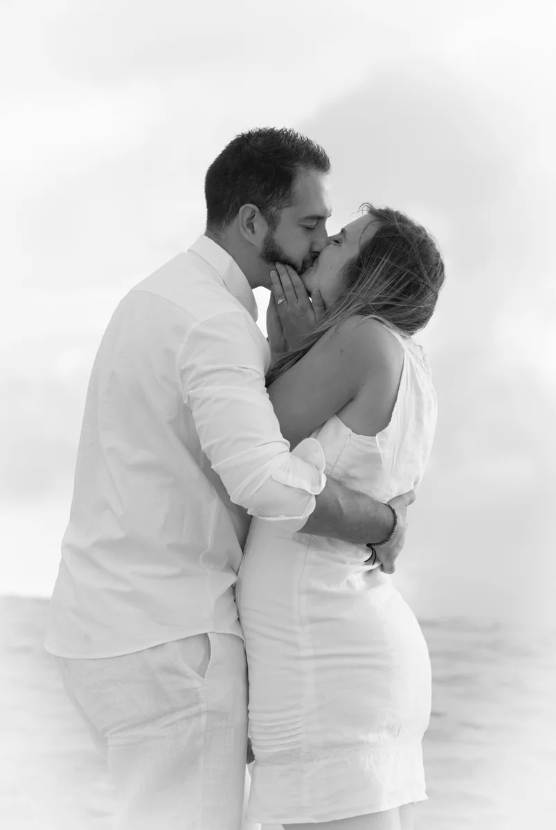 Portrait de couple en noir et blanc s'embrassant face à la mer